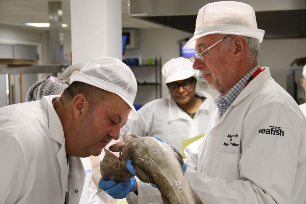 A person smelling a Cod which is being held by another person